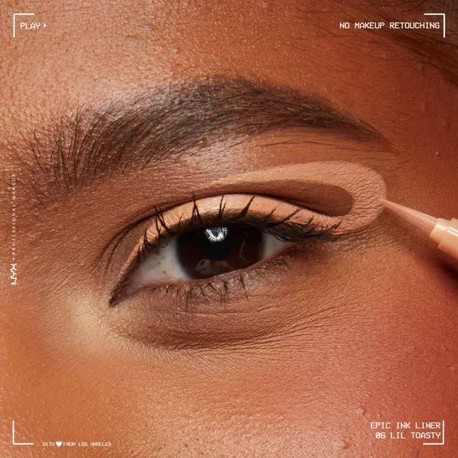 Close-up of a model's eye applying a nude eyeshadow shade, showcasing a smooth makeup look with no retouching.
