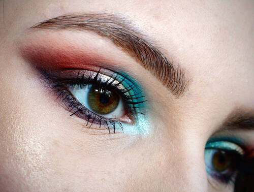 Otwarte oko kobiety w niebiesko-czerwonym makijażu w stylu cat eye.