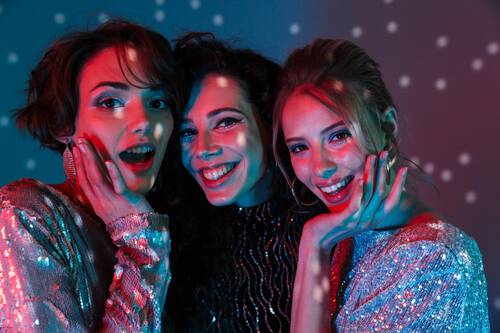 Trzy roześmiane kobiety na dyskotece pozują do wspolnego zdjęcia