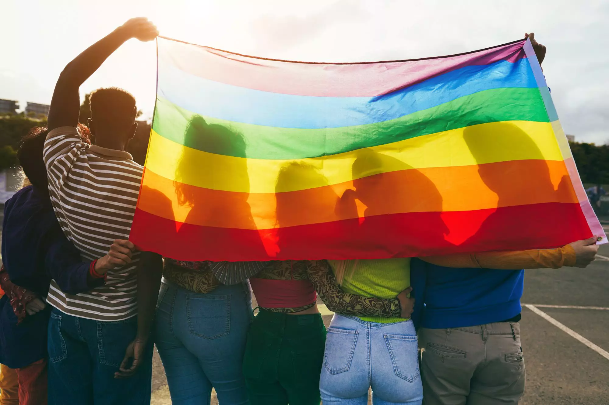 Grupa przyjacioł otulona tęczową flagą