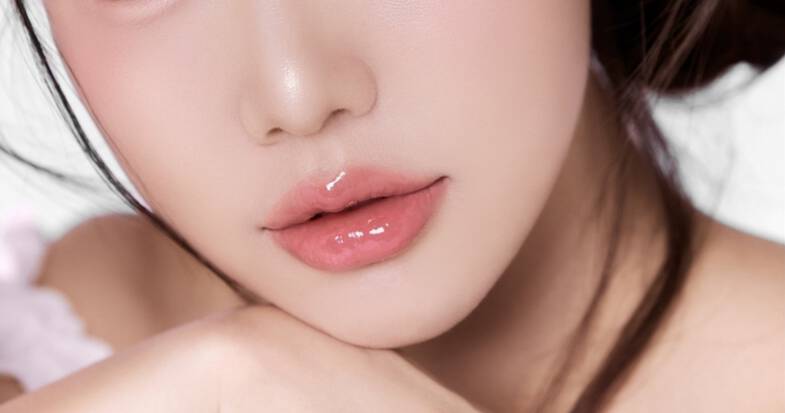 Zbliżenie na pokryte błyszczykiem usta młodej kobiety