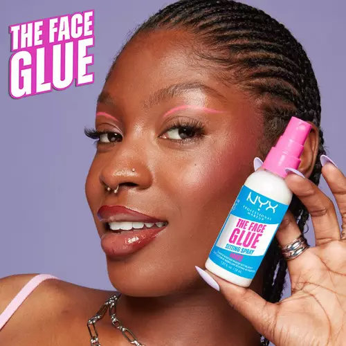 Młoda kobieta prezentuje buteleczkę sprayu The Face Glue Setting Spray od NYX PM.