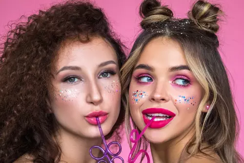 Dwie młode kobiety testują najnowsze trendy w makijażu przy pomocy rożnych kosmetykow