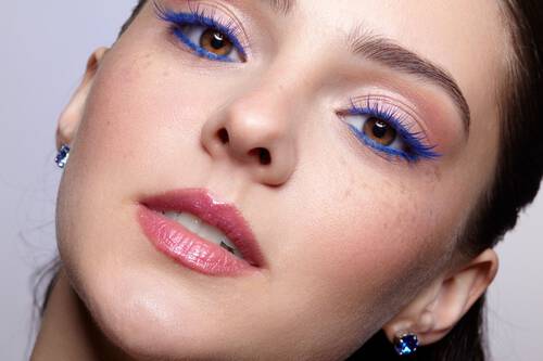 Roześmiana kobieta z kreskami na powiekach wykonanymi żołtym eyelinerem 