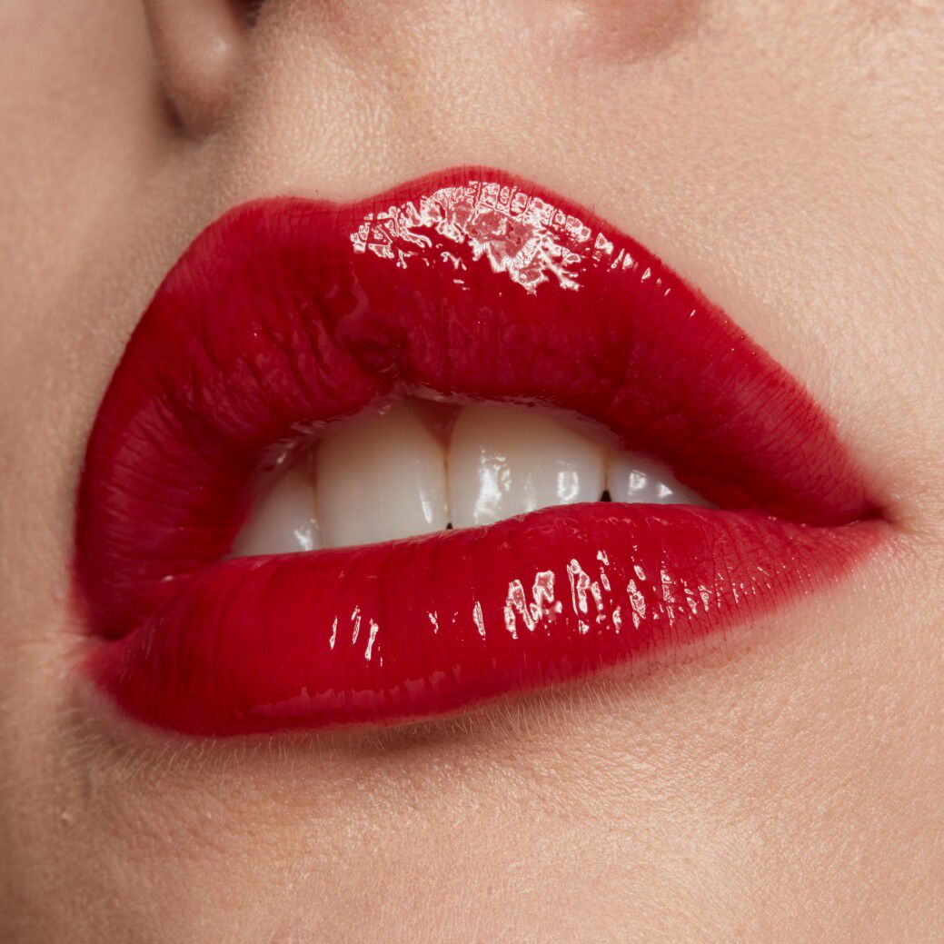 Usta kobiety pomalowane konturowką i błyszczącą czerwoną pomadką. 