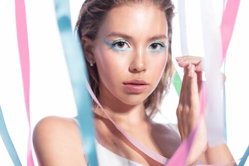 Kobieta w wyrazistym makijażu, w ktorym dominuje turkusowa kreska na gornej i dolnej powiece