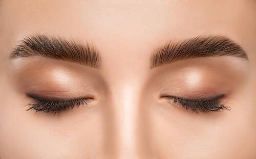 Zbliżenie na twarz kobiety, ktora ma wymodelowane, uczesane i pokolorowane brwi po laminacji