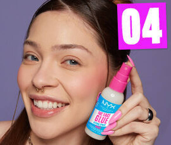 Kobieta z rożowymi paznokciami uśmiecha się, trzymając spray NYX \'The Face Glue\' na tle fioletowym.