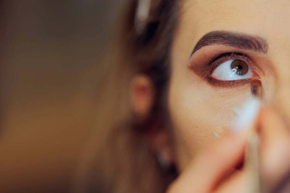 Zbliżenie na oko kobiety robiącej sobie brązowy makeup