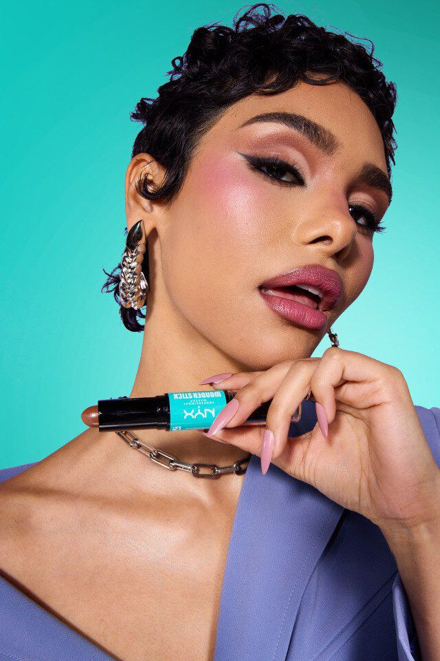 Kobieta z konturem na twarzy trzymająca kosmetyk NYX PM.