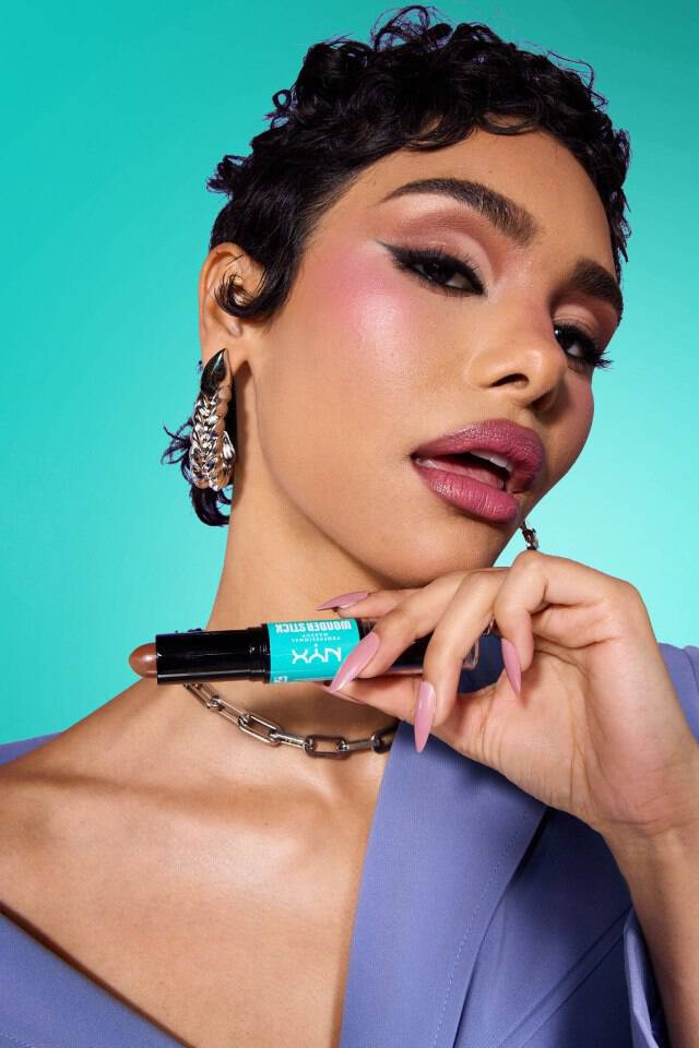 Kobieta z konturem na twarzy trzymająca kosmetyk NYX PM.