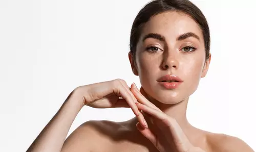 Młoda kobieta na białym tle, w delikatnym, rozświetlającym makeupie