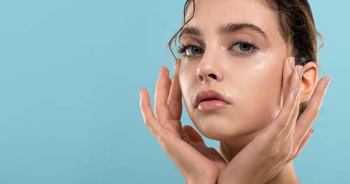 Młoda kobieta z clean girl make up na niebieskim tle.