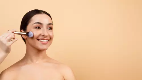 Młoda kobieta w makijażu nude z pędzlem przy twarzy.